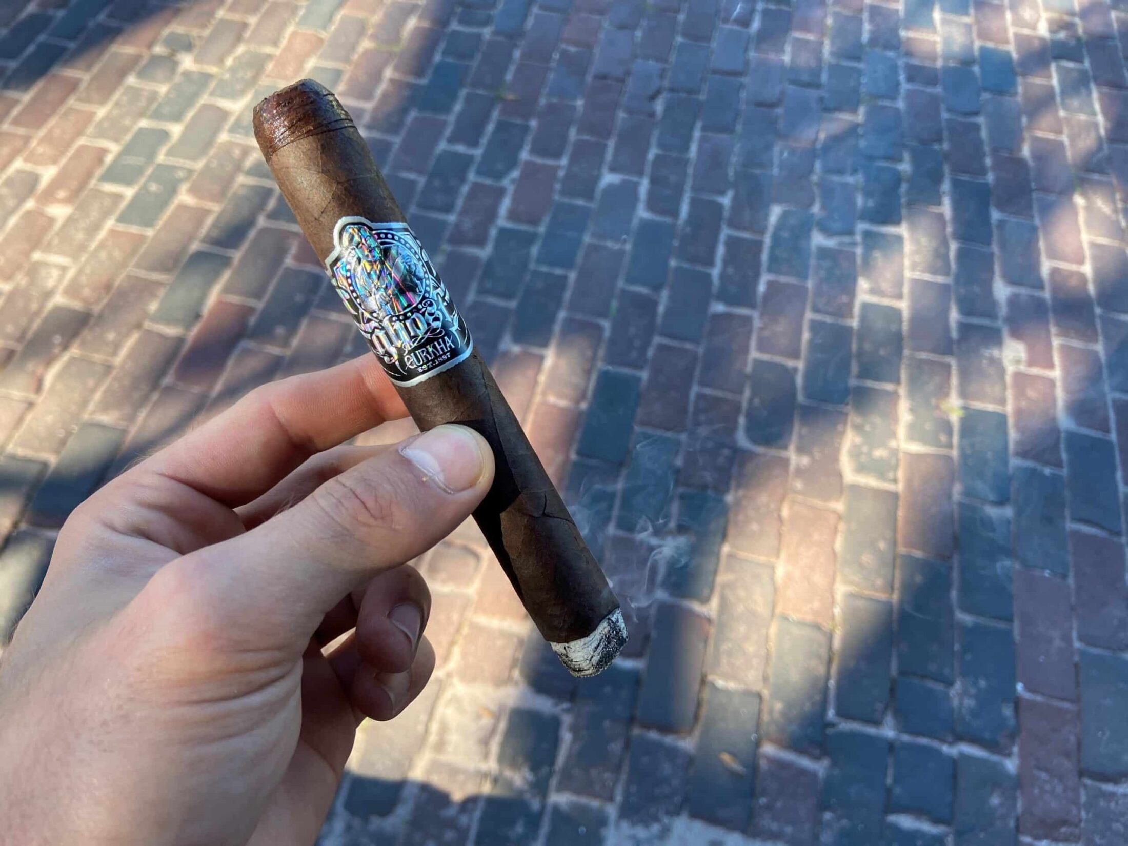 Hand holding a lightly-ashed Gurkha Ghost cigar